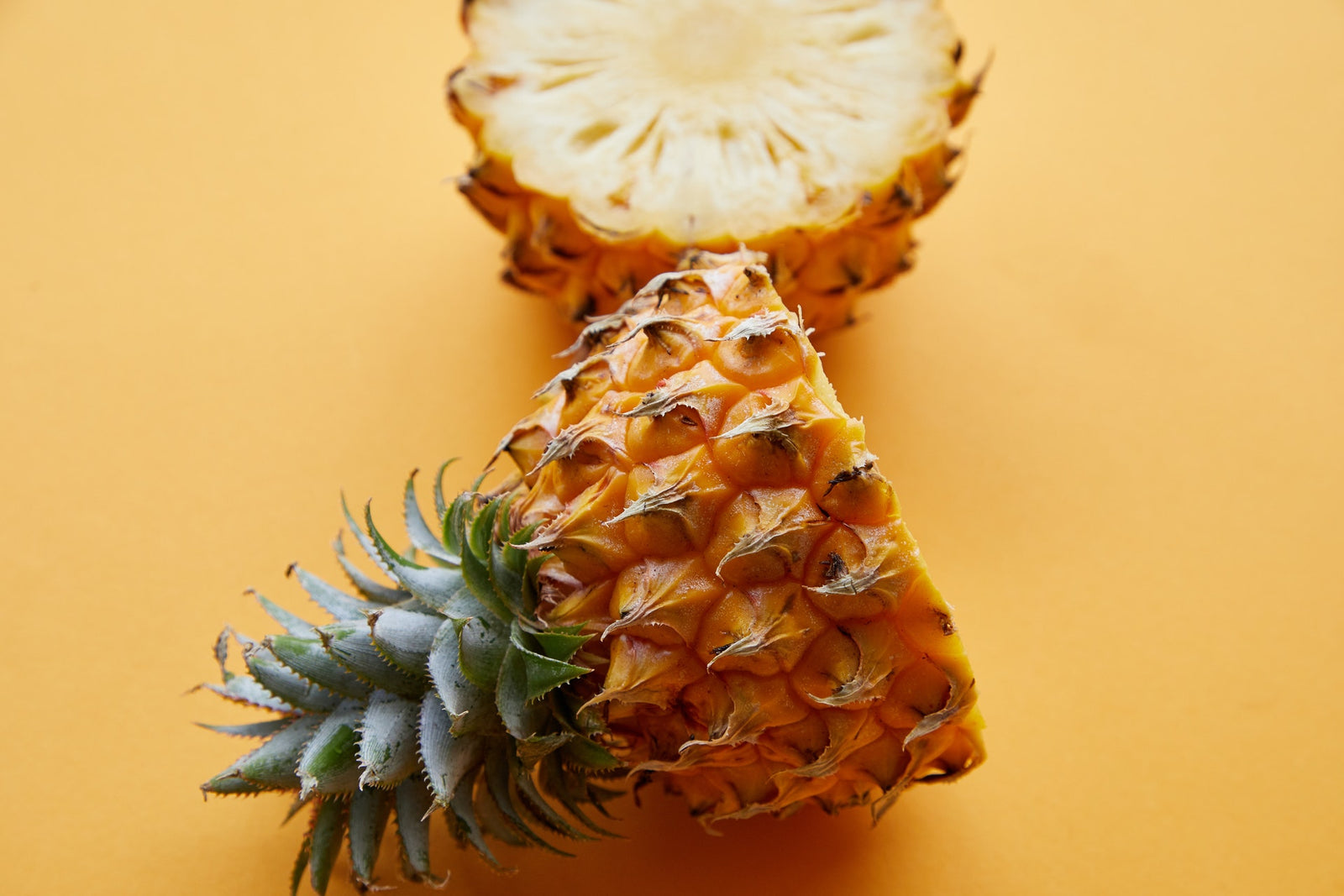 Image of a pineapple cut in half against a yellow background.