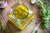 top view of a jar of pineapple chia vinaigrette dressing with herbs, onion, and peppercorn on the side on top of a wooden table