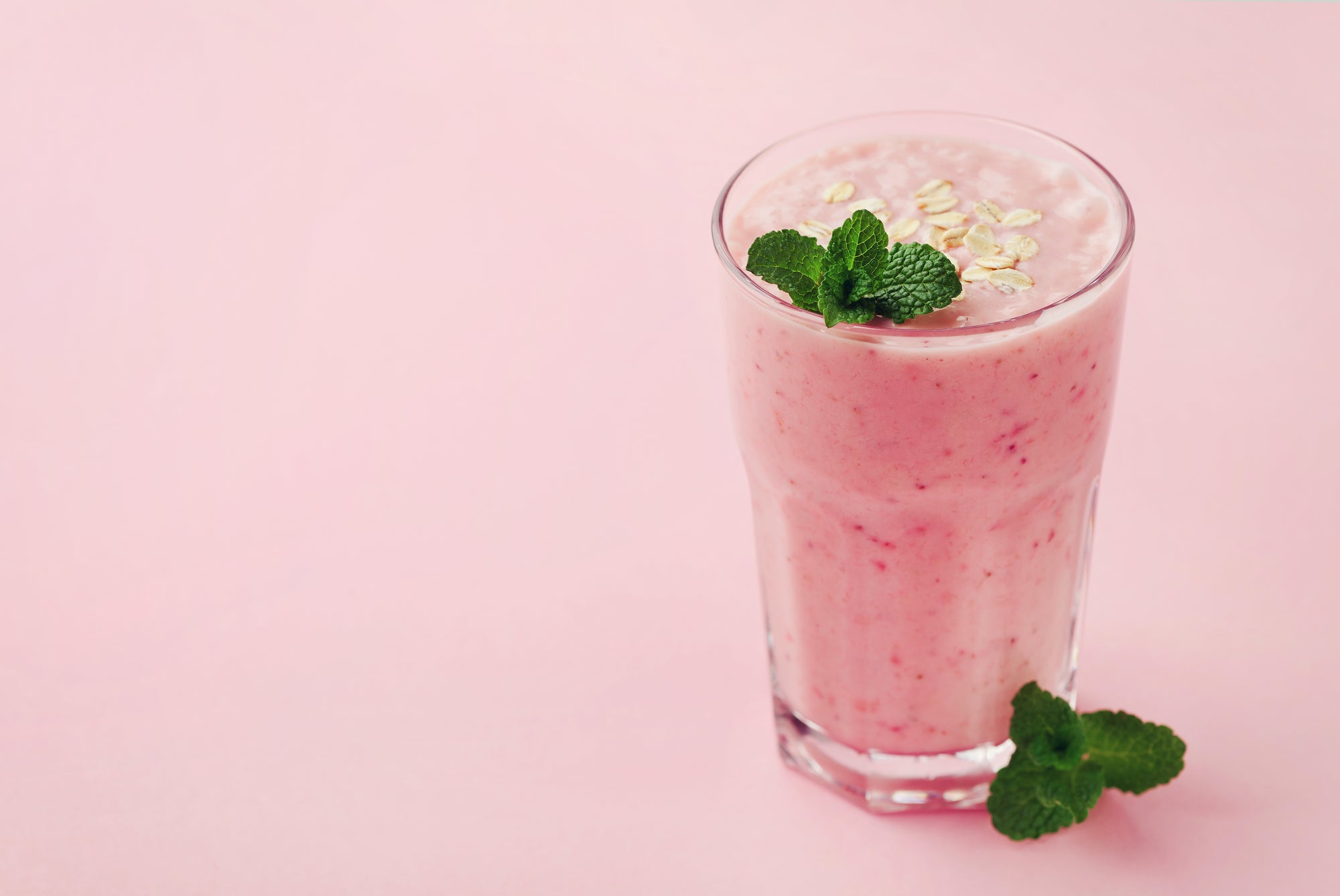 A glass of Tropical LIFE Smoothie with mint, next to mint leaves